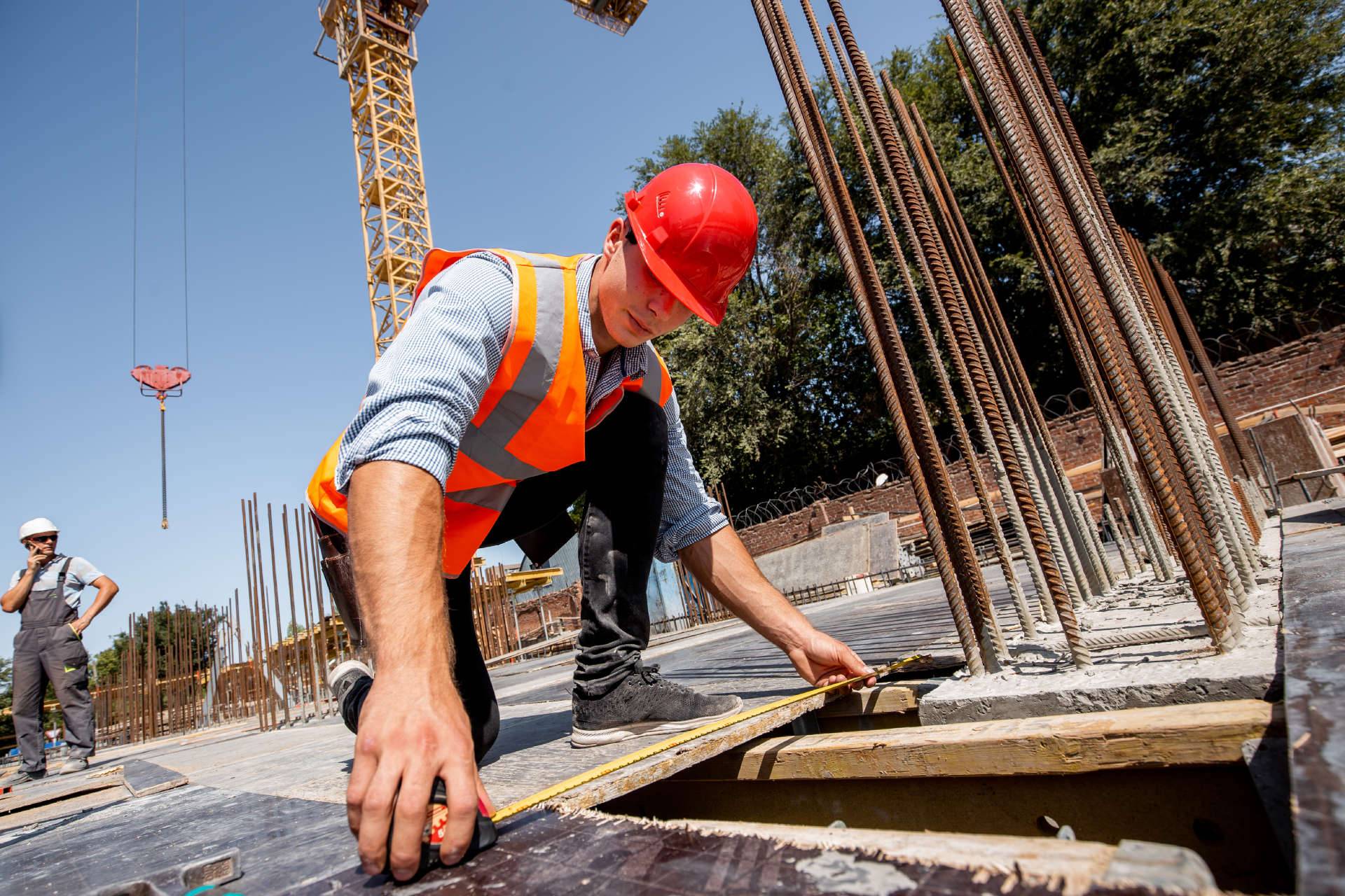 Worker tying reinforcing steel on concrete column cages at a construction site