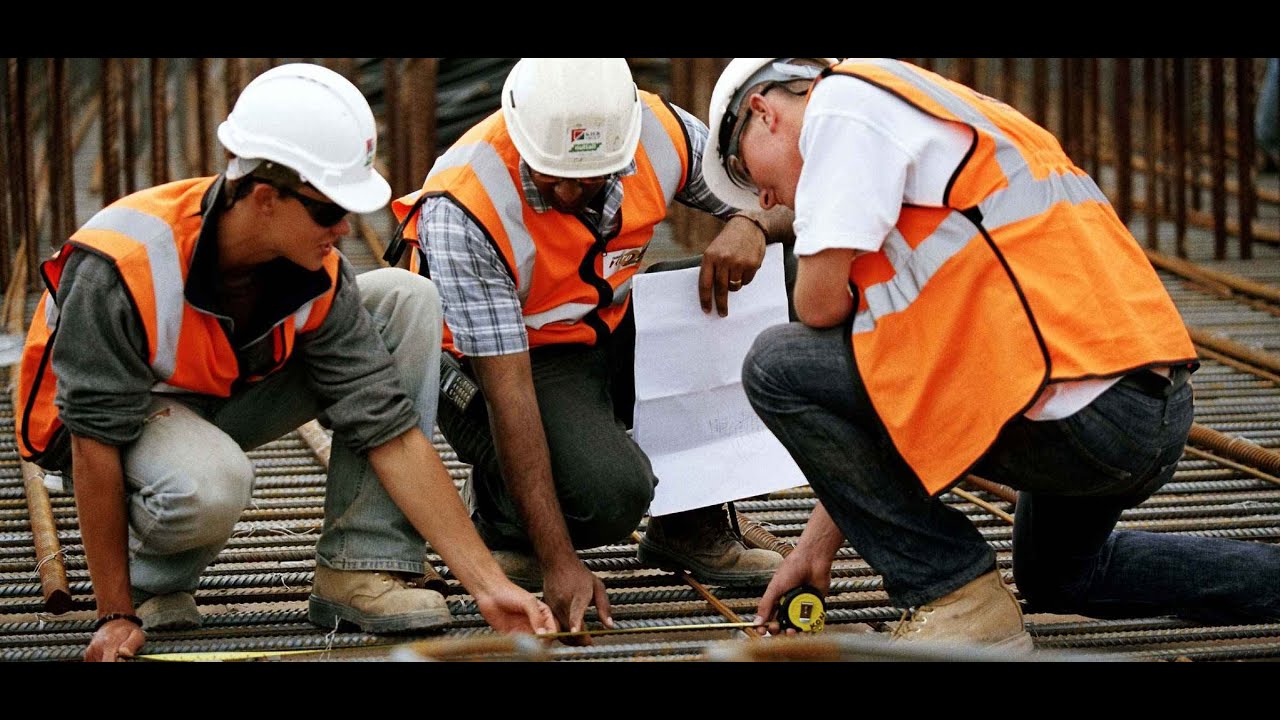 Construction workers reviewing drawings over a tied reinforcing steel mat