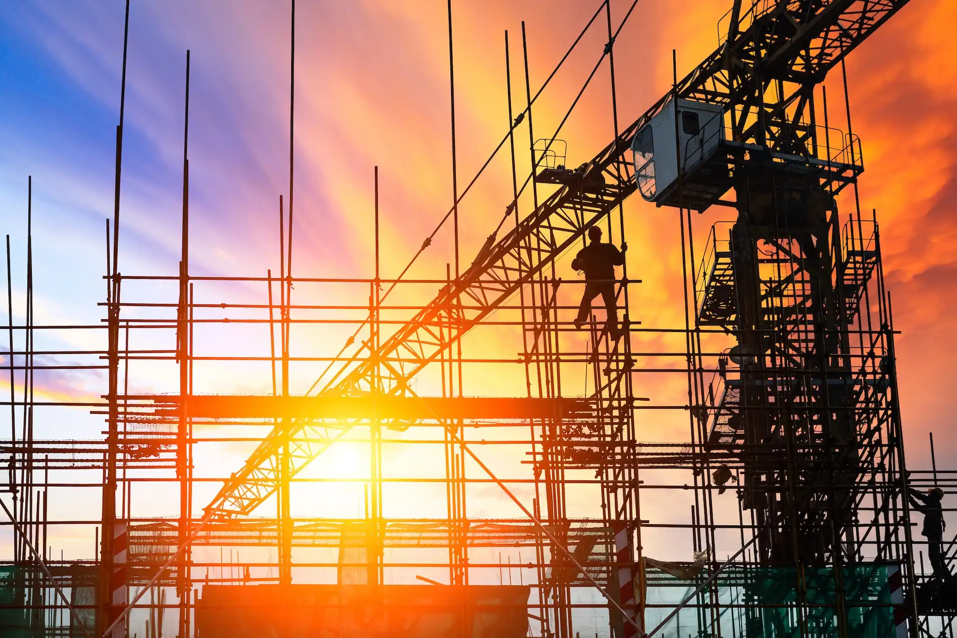 Structural steel frame and tower crane on a construction site at sunset