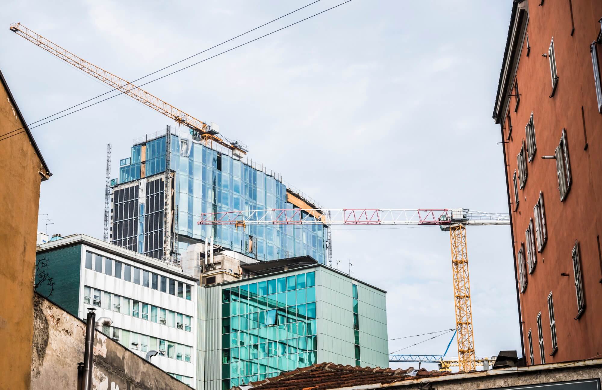 Tower cranes above steel-framed buildings under construction in a city